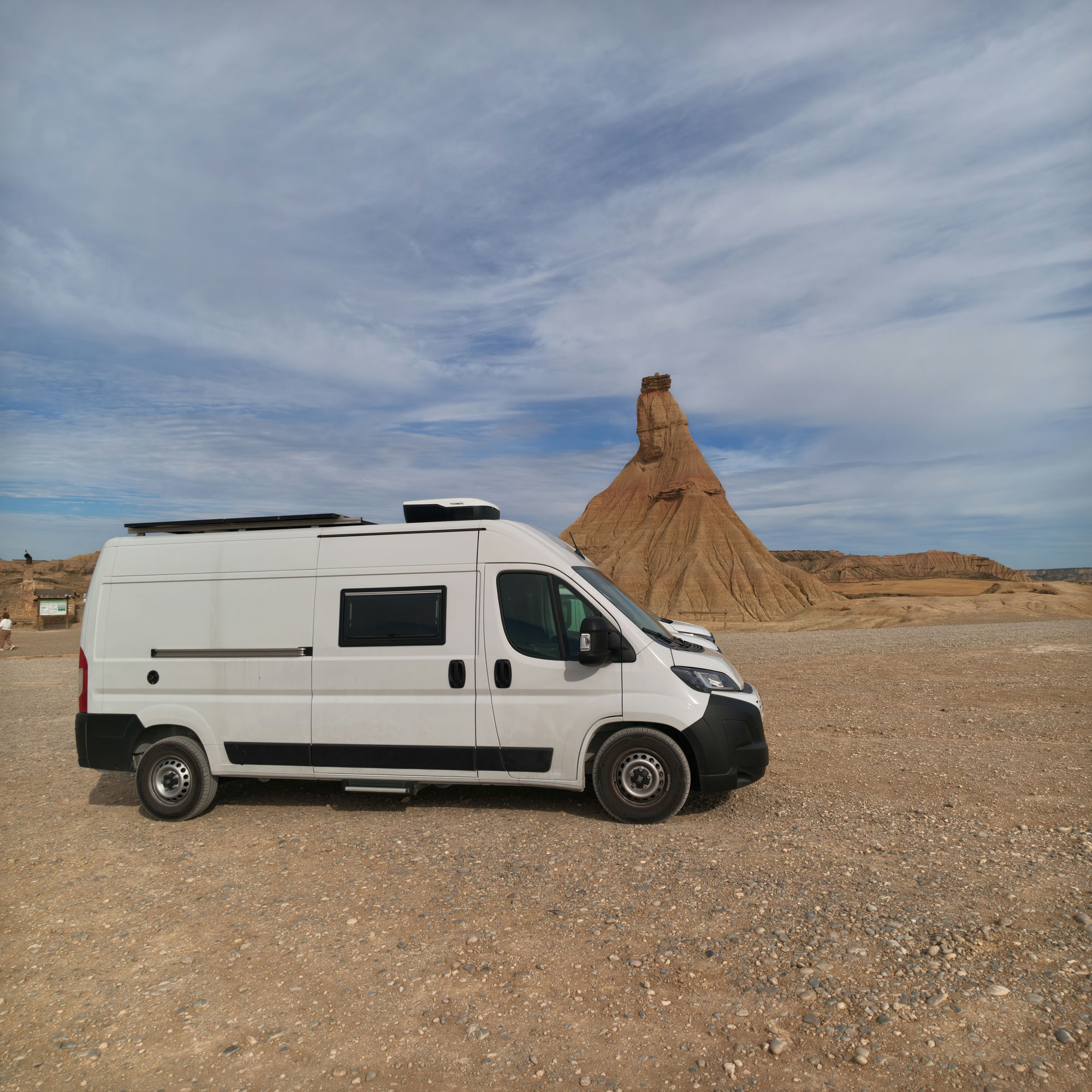 La Fitti, camper blanca aparcada frente a una formación rocosa en un paisaje árido