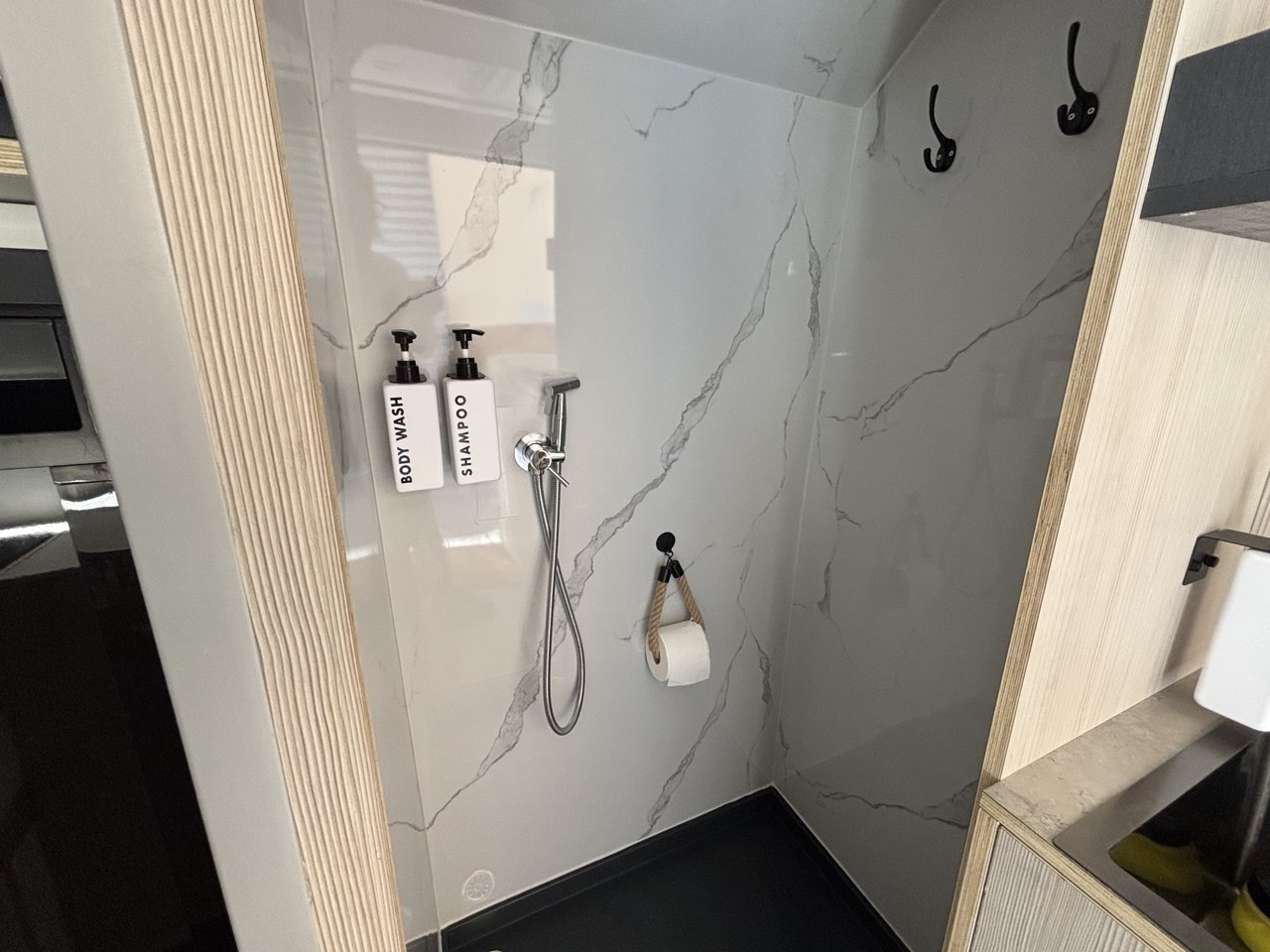 Ducha interior con pared de acabado marmoleado, grifería y dispensadores